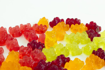 Group of gummy bears lying on the ground except one with isolate background