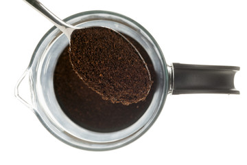 close-up of spoon with coffee power over coffee mug against white background.