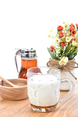 hot milk with honey, honey jar and honey dipper on white backgro