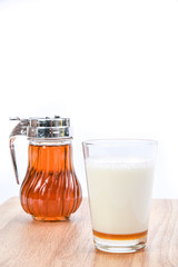 hot milk with honey, honey jar and honey dipper on white backgro