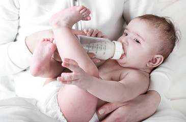 .The baby in diapers eating milk from the bottle