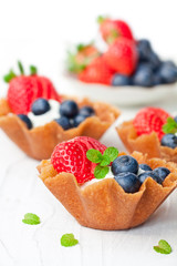 brandy  snaps baskets with soft cream cheese and berries on whit
