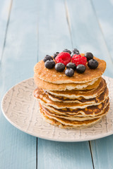 Pancakes with blueberries and raspberry on blue wood background 
