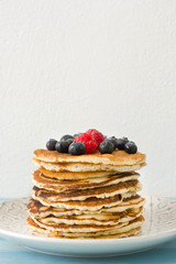Pancakes with blueberries and raspberry on blue wood background 
