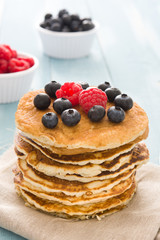 Pancakes with blueberries and raspberry on blue wood background 

