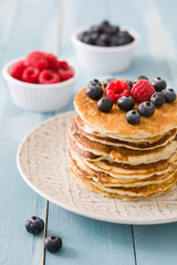 Pancakes with blueberries and raspberry on blue wood background 
