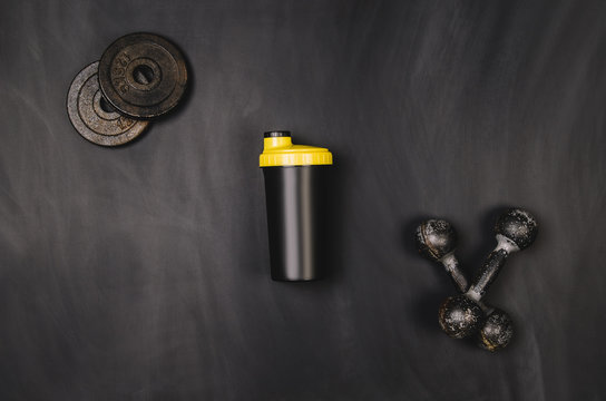 Iron dumbbells on a black chalkboard seen from above. Photo taken from above, top view. Conceptual image background for sport or fitness advertising. Horizontal image.