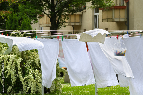 "Weiße Wäsche auf der Wäscheleine trocknet bei Wind im Innenhof