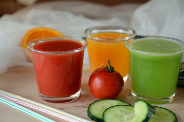 Fresh orange,tomato and cucumber smoothie on a glass on a wooden table