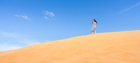 Fototapeta na wymiar Young woman standing and looking at sand dune desert landscape. Banner.