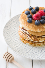 Pancake with blueberries and raspberries on white wood
