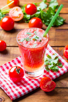 Tomato smoothie, fresh tomatoes and cilantro on wooden background