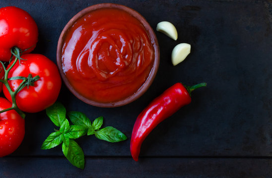 Tomato sauce salsa and ingredients, dark stone background. Top view