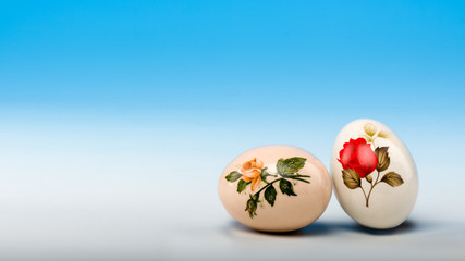 Two vintage decorated ceramic Easter eggs on graduated white-to-blue background