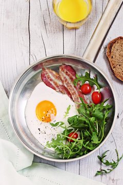 Fried egg with bacon,arugula and tomatoes. 
