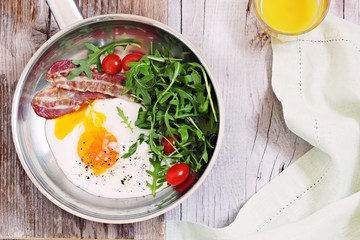 Fried egg with bacon,arugula and tomatoes. 