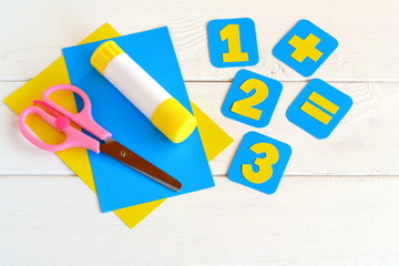 Handmade paper cards with numbers, scissors, paper sheets, glue on a white background. Education concept