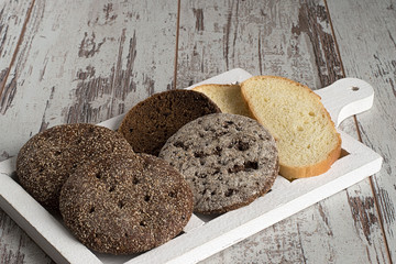 Bread.  Bread, white and black on a cutting board on a light wooden background.