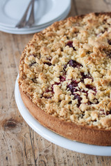 Homemade fresh sweet cherry crumble pie with whole wheat flour on a wooden table background ready to eat, closeup