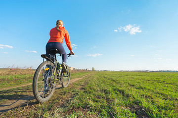 Fototapeta premium Bike riding - Young woman trying to ride on a bicycle in nature offroad