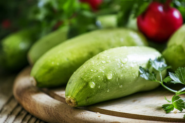 Fresh zucchini on the old wooden background with parsley, dill a