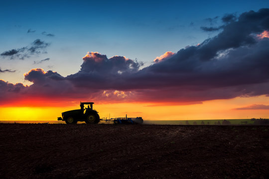 Fototapeta Farmer in tractor preparing land with seedbed cultivator