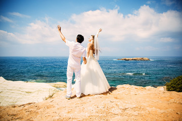 Elegant bride and groom walking on the beach, wedding ceremony, Mediterranean Sea. 