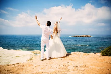 Gordijnen Elegant bride and groom walking on the beach, wedding ceremony, Mediterranean Sea.  © siyatsky
