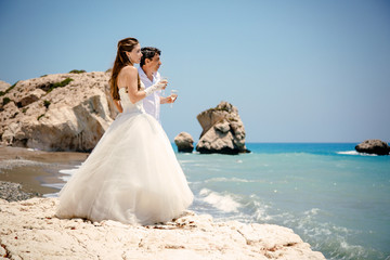 Fototapeta na wymiar bride and groom with glasses of champagne on the beach Mediterranean Sea