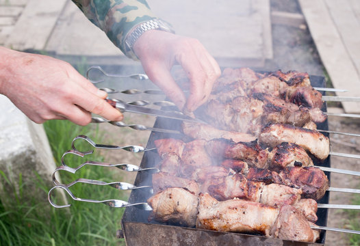 Man cooking, only hands, he is cutting meat or steak for a dish. Delicious grilled meat on grill. Barbecue weekend. Selective focus