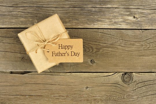 Brown Fathers Day gift box with tag on a rustic wood background