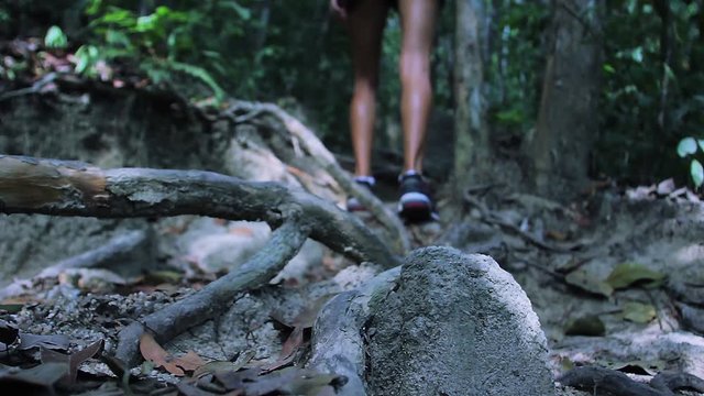 Woman running in jungle. Female feet in sneakers walking outdoors.