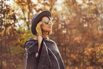 Portrait of a young, elegant woman looking away from the camera. Photogaph taken in autumn surrounding.