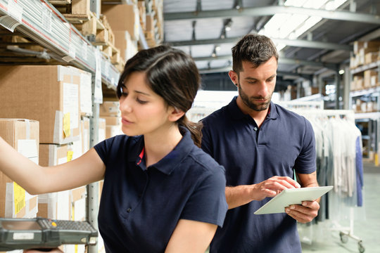 Warehouse workers using digital tablet to prepare order in distribution warehouse