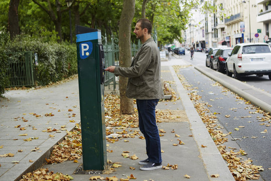 Mid adult man using parking meter in street