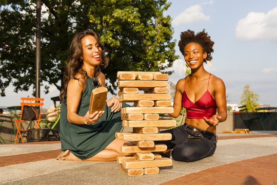 Young women playing with building blocks on floor