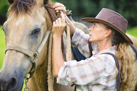 Mature woman securing horses reigns