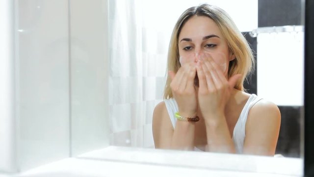 Closeup of young woman face cleaning skin.