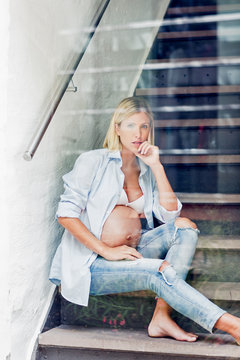 Portrait of full term pregnancy young woman sitting on stairway