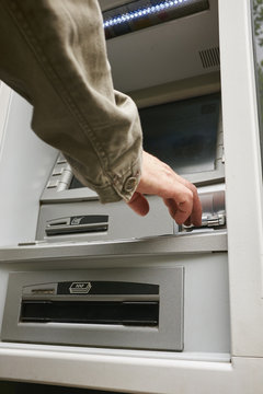 Mid adult man using cash machine, focus on hands
