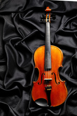 Fototapeta na wymiar aged violin on dark fabric texture