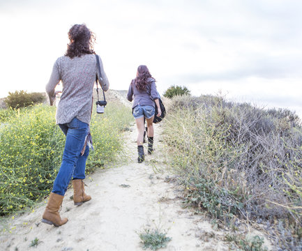 Rear view of two adult sisters walking along dirt track