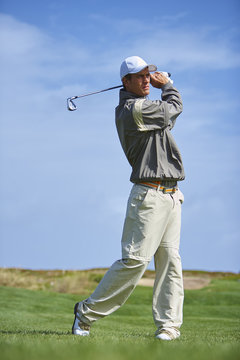 Full length front view of golfer holding golf club taking golf swing