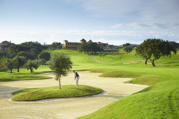 Golfer on island in sand trap preparing golf swing