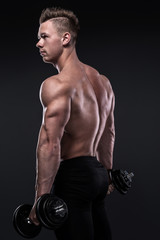 Obraz na płótnie Canvas Bodybuilder doing exercises with dumbbells