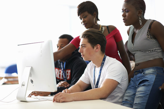 Group of students working on desktop computer in classroom