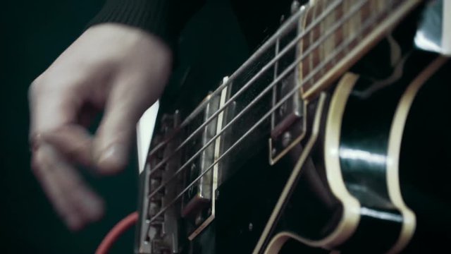 Musician playing bass guitar at studio, close up, slow motion