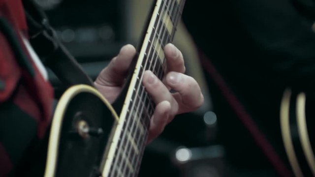Musician playing electric guitar solo at studio, close up, slow motion