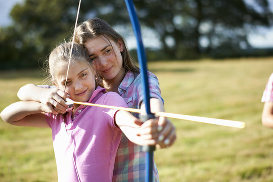 Girl learning archery from teenage sister