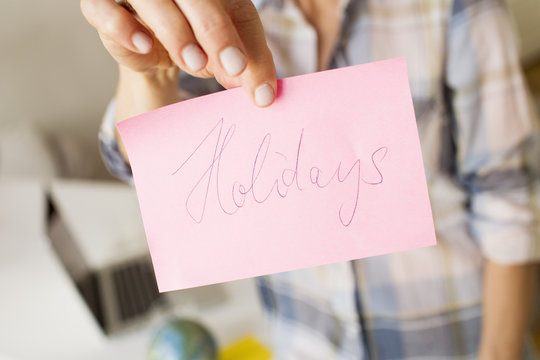 Cropped view of mature womans hands holding handwritten note with the word holidays